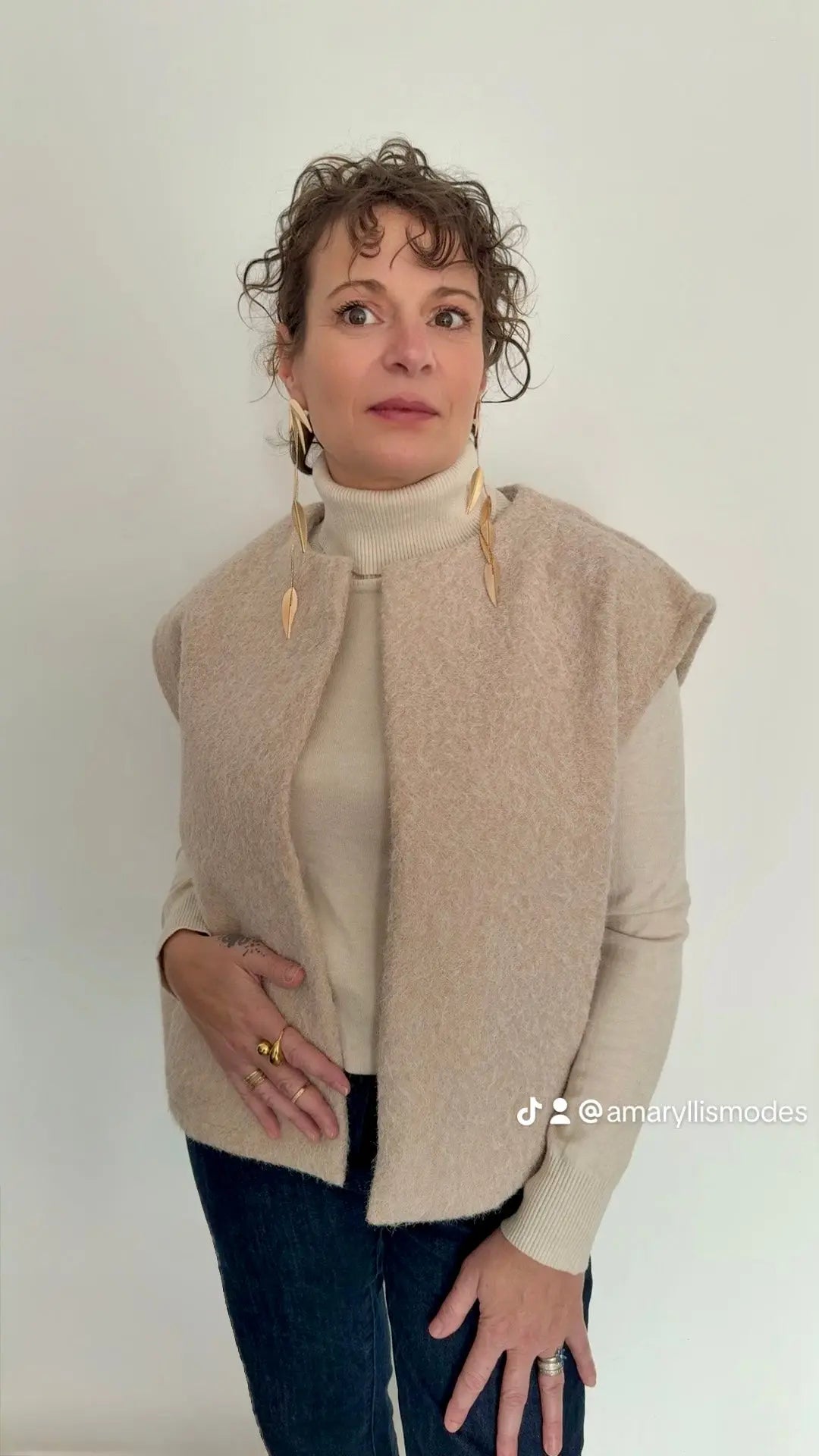 alt="Gilet sans manches beige clair en polyester texturé, coupe droite, porté sur un pull col roulé crème – collection femme Amaryllis Modes