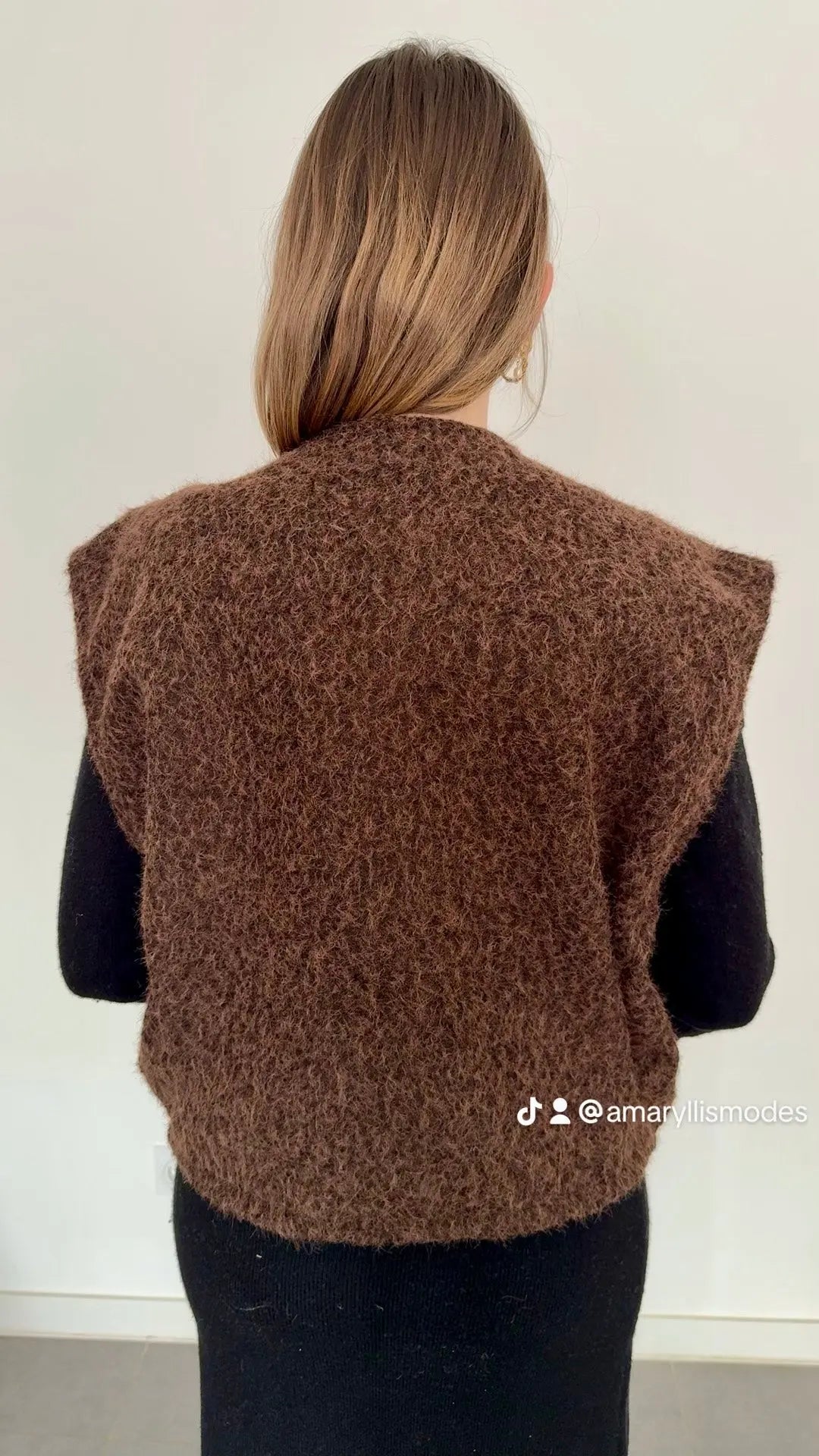 Gilet sans manches brun chocolat en polyester, texture bouclée, coupe droite, épaules larges, porté sur un pull noir – collection femme Amaryllis Modes